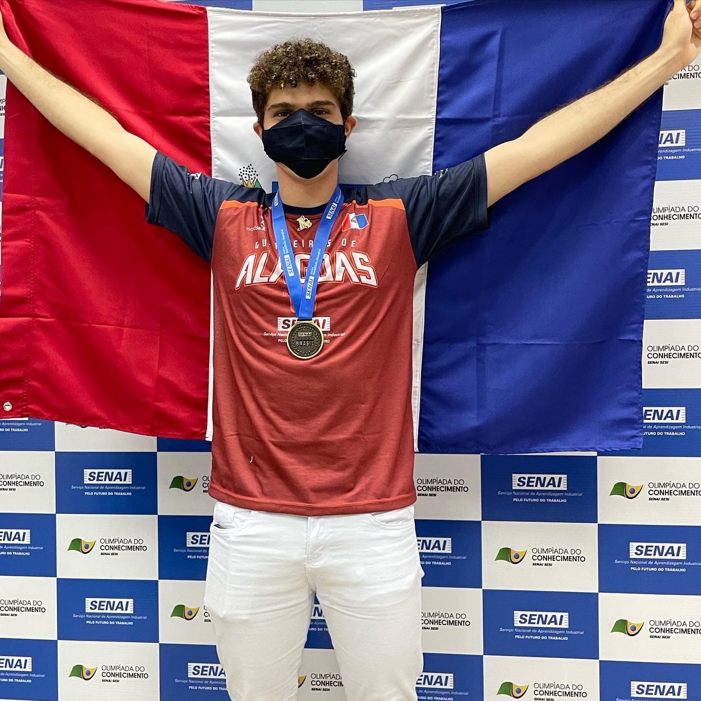Mikael with the WorldSkills Brasil gold medal, holding the Alagoas flag