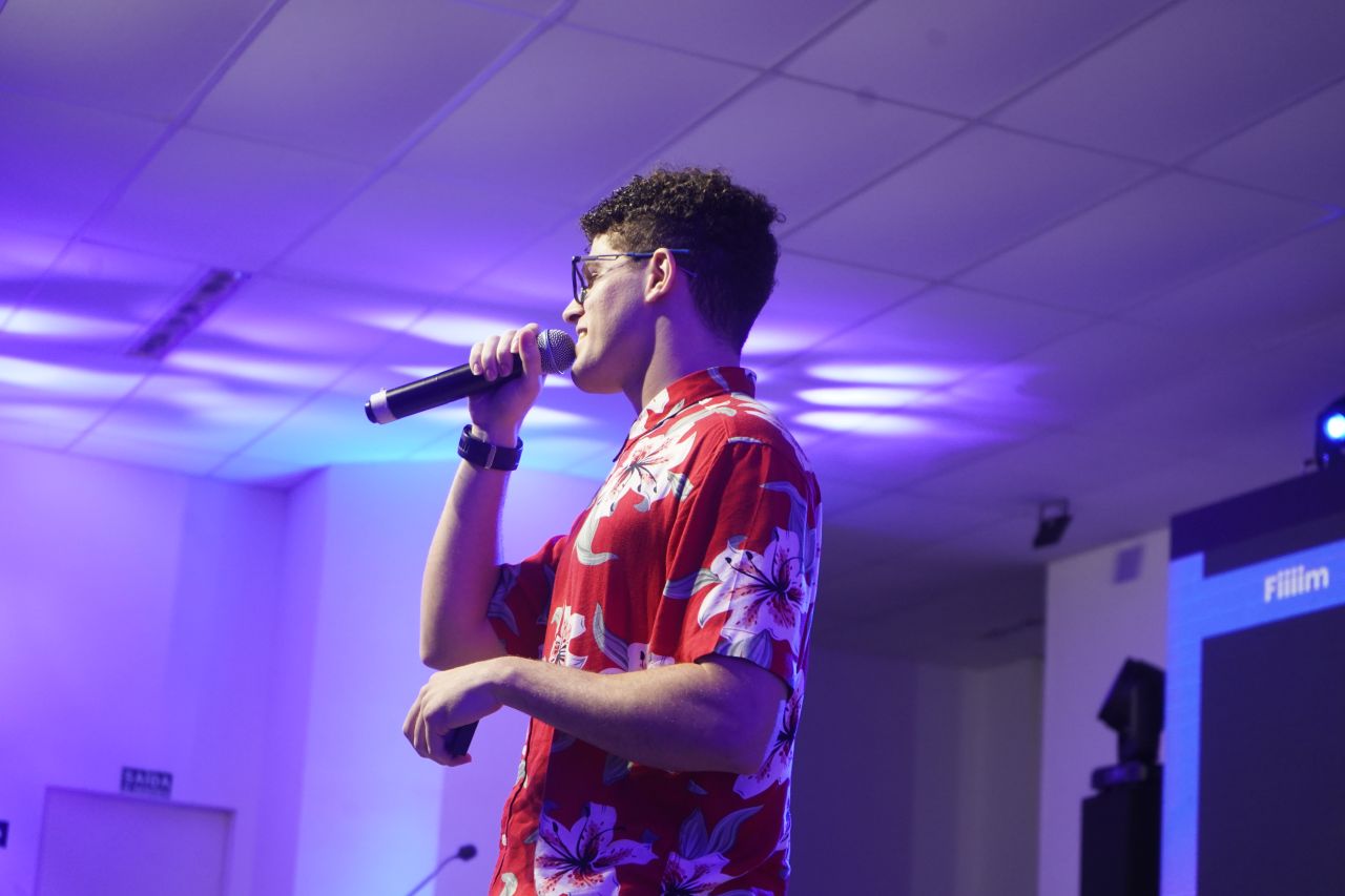 Mikael Ribeiro Simoes speaking on stage with a microphone